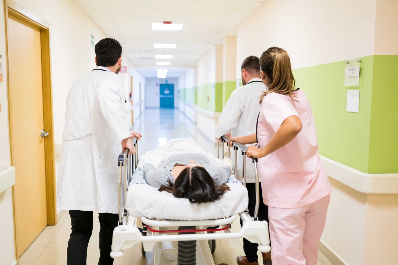 doctors-nurse-pushing-female-patient-stretcher-corridor-hospital-min-scaled